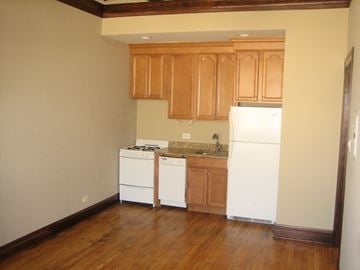 Chicago apartment for rent - an empty kitchen with white appliances and wooden floors