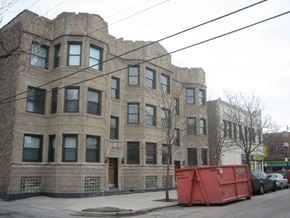 Chicago apartment for rent - a large brick apartment building with a red dumpster on the street