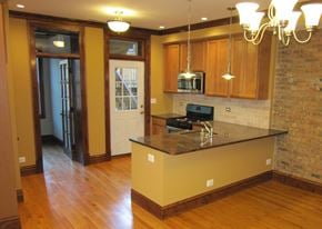 Chicago apartment for rent - a kitchen with a large island and a door to a living room