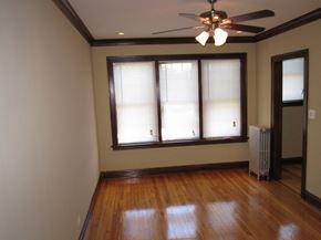 Chicago apartment for rent - an empty living room with a ceiling fan and windows