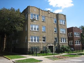 Chicago apartment for rent - a tall brick building with a black fence in front of it