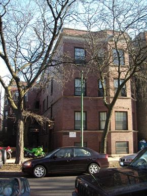 Chicago apartment for rent - a tall brick building with cars parked in front of it