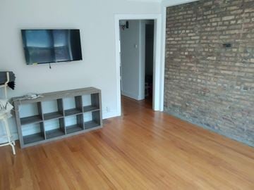 Chicago apartment for rent - a living room with wooden floors and a tv on the wall