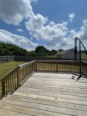 Oak Grove house for rent - A wooden deck with a black railing and a small building in the background.