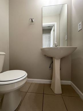 Clarksville house for rent - A white toilet sits next to a pedestal sink in a bathroom.