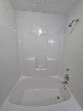 Clarksville house for rent - A white bathroom with a tub and shower.