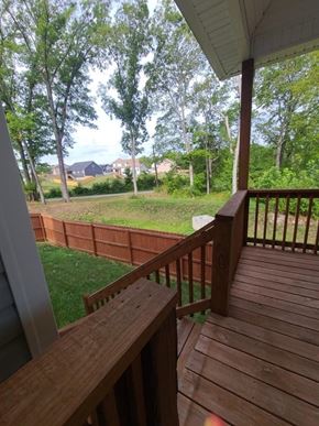 Clarksville house for rent - A wooden deck with a bench overlooks a grassy area.
