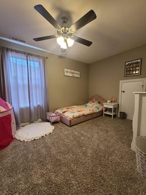 Clarksville house for rent - A bedroom with a bed, a ceiling fan, and a carpeted floor.