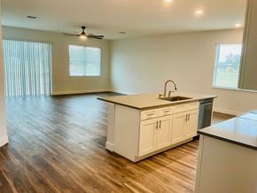 Orlando apartment for rent - an empty living room with a kitchen and a ceiling fan