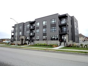Kanata apartment for rent - A grey apartment building with balconies and a front yard.
