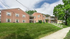 Delaware apartment for rent - a large brick apartment building with a green lawn and a sidewalk