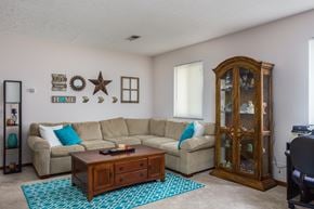 Delaware apartment for rent - A living room with a beige couch, a wooden coffee table, and a glass cabinet.