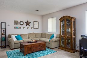 Delaware apartment for rent - A living room with a beige couch, a wooden coffee table, and a glass cabinet.