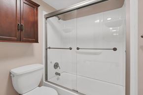Delaware apartment for rent - A white toilet sits next to a walk-in shower with a glass door.