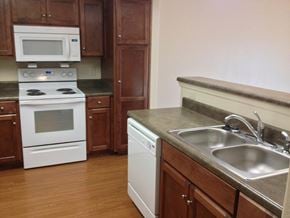 Hahira apartment for rent - a kitchen with white appliances and wooden cabinets