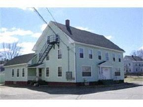 Laconia apartment for rent - A white house with a black roof and a green staircase.