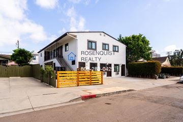 San Diego apartment for rent - the exterior of rosemount realty with a yellow fence and a white building