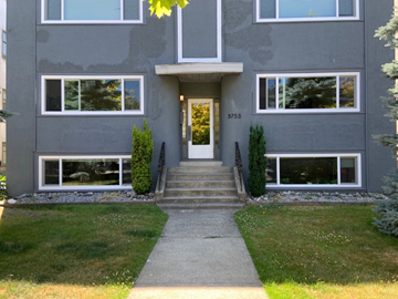 Vancouver apartment for rent - the front of a gray house with white windows and a sidewalk