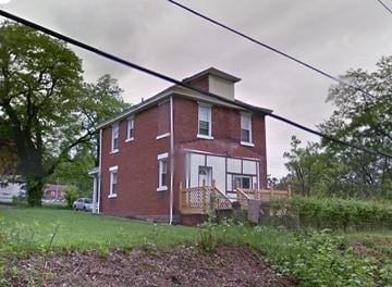 Clairton house for rent - a red brick house with a porch on a hill