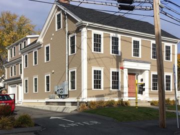 Danvers apartment for rent - A two-story building with a red door and a red car parked in front.