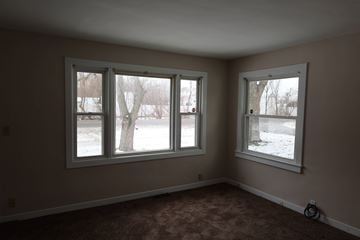 Gary house for rent - a living room with three windows and a carpet