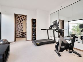 Oklahoma City apartment for rent - A modern home gym with a treadmill, exercise bike, and weights.