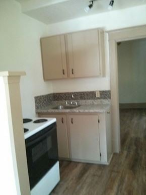 Victoria apartment for rent - an empty kitchen with white cabinets and a stove