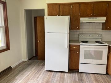 Uniontown apartment for rent - A white refrigerator stands in a kitchen with wooden cabinets and a white stove.