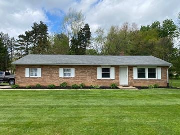 Uniontown apartment for rent - A small house with a white door and windows is surrounded by a green lawn.