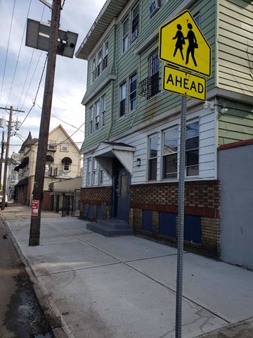 Newark apartment for rent - A pedestrian crossing sign is displayed on a pole on a street.