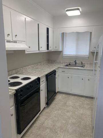 Raleigh apartment for rent - A kitchen with white cabinets and a black stove top oven.