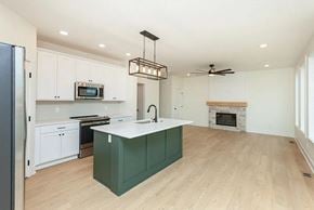 Waukee house for rent - A kitchen with a green island and white cabinets.