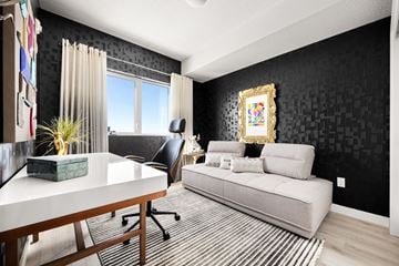 Calgary apartment for rent - A black and white living room with a couch, chair, and a painting on the wall.