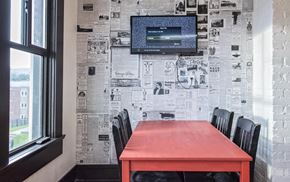 Vancouver apartment for rent - a dining room with a red table and black chairs and a wall covered in newspaper
