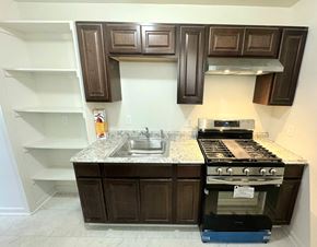 Washington apartment for rent - a kitchen with brown cabinets and a sink and a stove