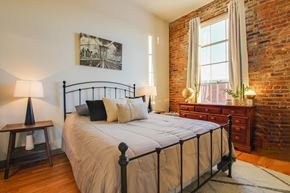 Decatur apartment for rent - A bedroom with a large bed and a brick wall.