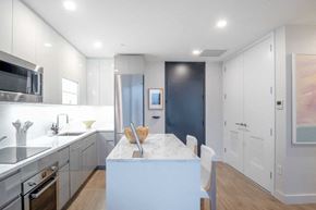 Woodside apartment for rent - a kitchen with white cabinets and a marble counter top