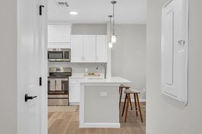 Boylston apartment for rent - a kitchen with white cabinets and a white island with stools