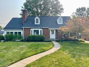 Louisville house for rent - A house with a brick facade and a white door is surrounded by a well-kept lawn.