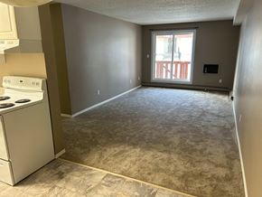 Prince Albert house for rent - a kitchen and an empty living room with a stove and a window