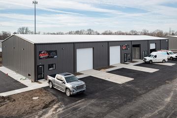Indianapolis apartment for rent - A silver truck is parked in front of a grey building with a black roof.