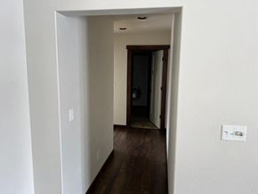 Bozeman house for rent - a hallway with white walls and wood floors and a door to a bathroom