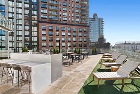 Long Island City apartment for rent - a roof terrace with tables and chairs and a building in the background