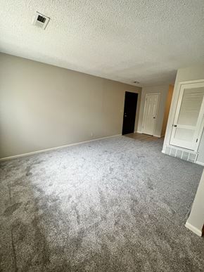 Lincoln apartment for rent - an empty living room with carpeting and a door to a bedroom