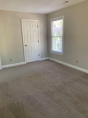 Cary house for rent - A room with a carpeted floor, a white door, and a window with a view of trees outside.