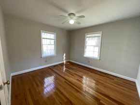 Raleigh house for rent - an empty living room with wooden floors and a ceiling fan