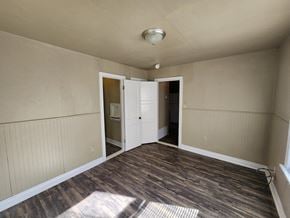 Harrah house for rent - a empty living room with wood floors and a door to a kitchen