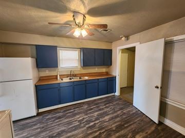 Harrah house for rent - a kitchen with blue cabinets and a ceiling fan