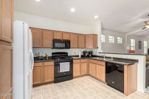 Buckeye house for rent - a kitchen with wooden cabinets and black appliances