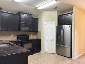 Killeen house for rent - a kitchen with black cabinets and stainless steel appliances